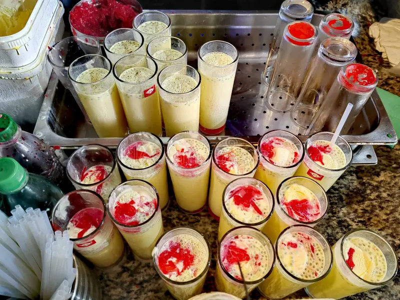 A glass of alouda drink with basil seeds and colourful layers of milk and syrup