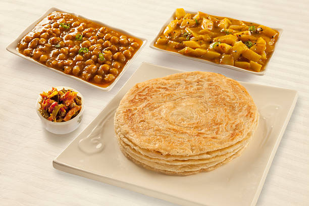 A plate of dholl puri flatbread served with curry and chutney